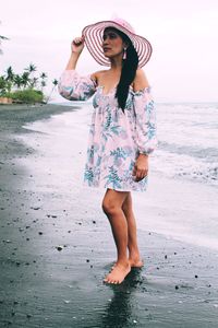 Full length of woman standing at beach against sea