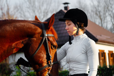 Side view of young woman riding horse on field