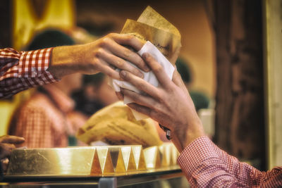 Cropped hands of man giving food to customer at market