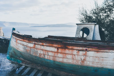 Abandoned boat moored on sea against sky