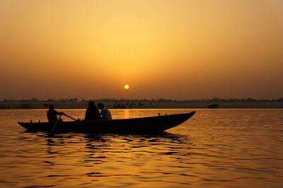 People on boat at ganges river against sky during sunset