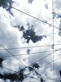 Low angle view of power lines against cloudy sky