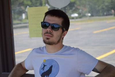 Portrait of young man wearing sunglasses while standing in car