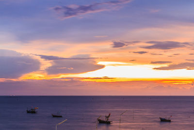 Boats in sea at sunset