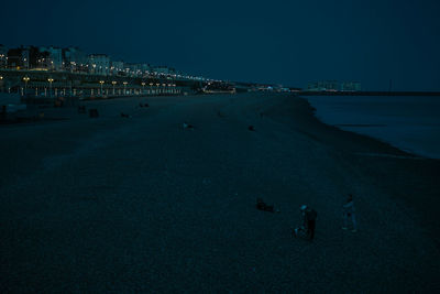 Aerial view of illuminated city by sea against sky at night
