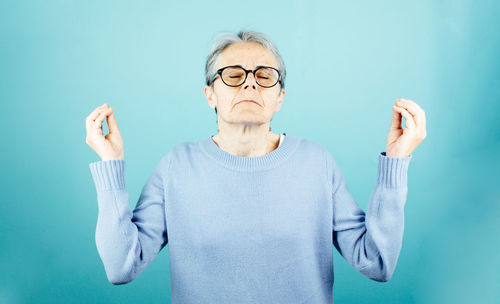 Portrait of young woman gesturing against wall