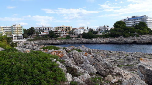 Scenic view of sea by buildings against sky