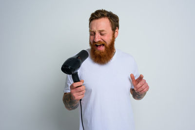 Portrait of man holding camera against white background