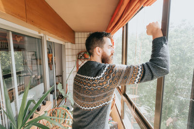 Side view of woman looking through window