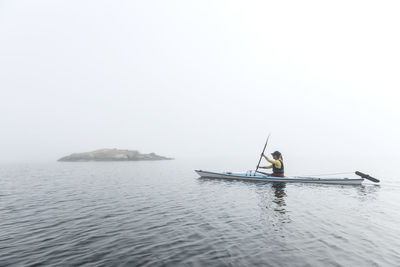 Woman paddling in fog, sweden