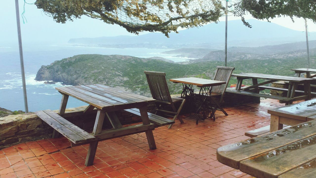 mountain, water, mountain range, empty, built structure, tranquility, tranquil scene, absence, railing, sky, sea, architecture, scenics, nature, lake, chair, bench, day, table, beauty in nature