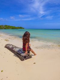 Boy sitting on beach against sky