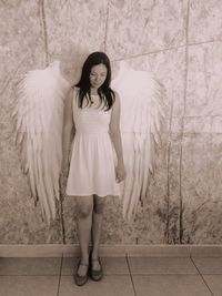 Woman in angel wings standing against wall