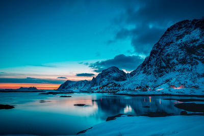 Scenic view of lake and snowcapped mountains against sky during sunset