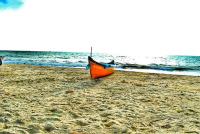 Boat moored on beach against clear sky