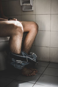 Low section of man sitting bathroom at home