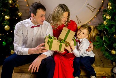 Portrait of smiling young woman holding christmas tree