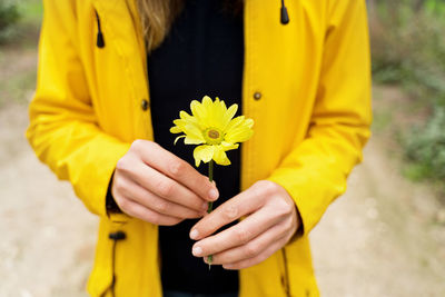 Midsection of woman holding yellow flower