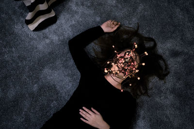 High angle view of woman with face covered by string lights