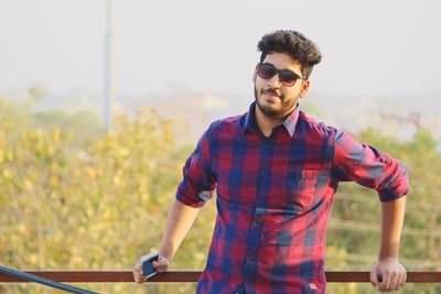 Portrait of young man wearing sunglasses while standing outdoors