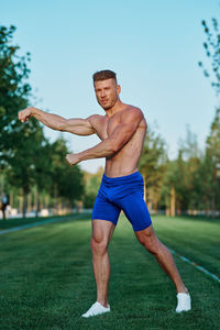 Portrait of shirtless man exercising on field