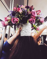 Close-up of woman carrying pot with flowers on head in bus