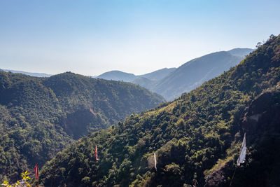 Mountain range covered with green forests and misty blue sky at morning from flat angle