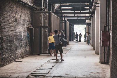 Rear view of people walking on footpath amidst buildings