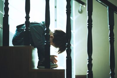 Side view of young woman looking through window