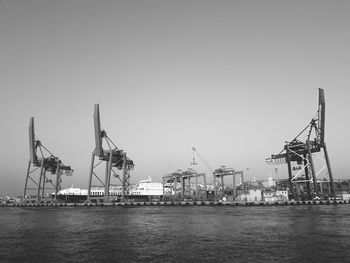 Cranes at commercial dock against clear sky