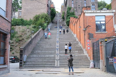 People walking on staircase amidst buildings in city