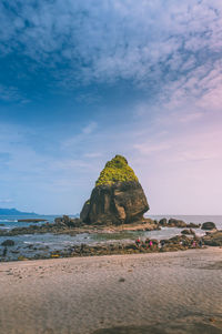 Rock formation on beach against sky