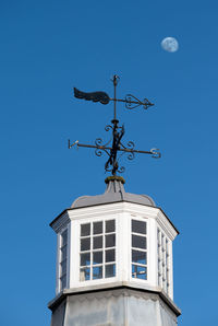 Low angle view of weather vane against blue sky