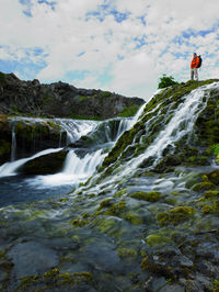 Man standing above beautiful waterfall at thjorsardalur