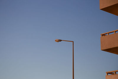 Low angle view of street light and building against clear blue sky