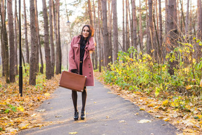 Woman with umbrella walking on footpath in forest