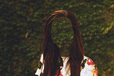 Digital composite image of faceless woman standing against plants