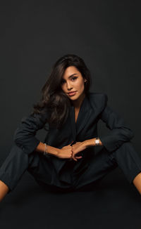 Portrait of young woman against black background