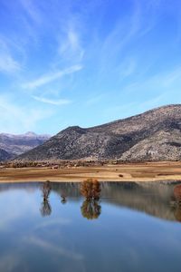 Scenic view of lake and mountains against blue sky