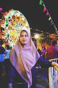 Woman looking away while standing by railing at night