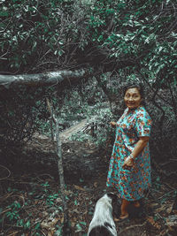 Full length of woman standing against trees in forest