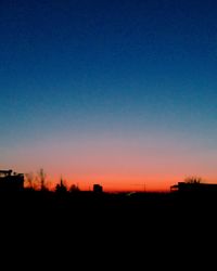 Silhouette trees against clear sky during sunset