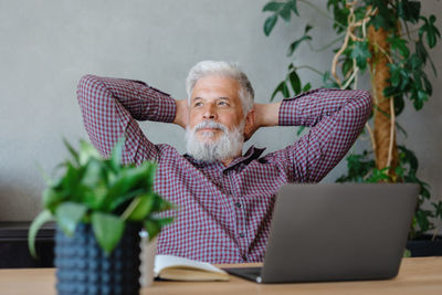 Businessman with hands behind head laptop on table in office