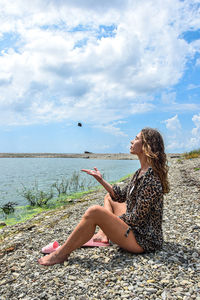Woman sitting at beach against sky