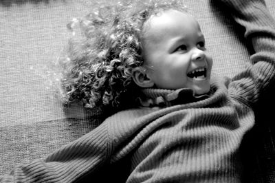 High angle view of cheerful girl lying on carpet at home