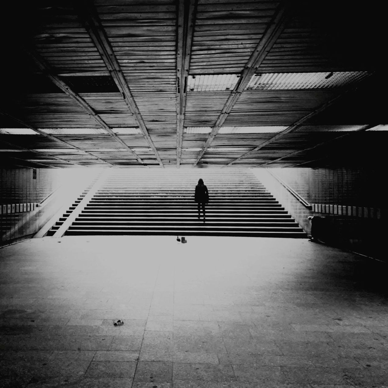 REAR VIEW OF MAN WALKING ON CORRIDOR