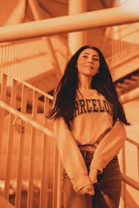 Portrait of young woman sitting on railing