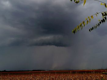 Scenic view of field against storm clouds