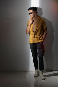 Young man looking away while standing against wall