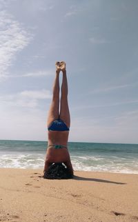 Upside down image of woman exercising on sand at beach